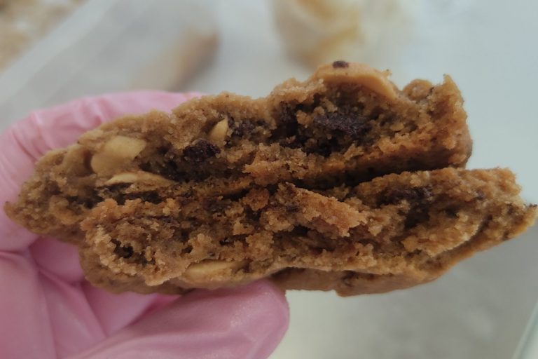 Ein aufgeschnittener Cookie mit Schokoladenstückchen und Erdnüssen.